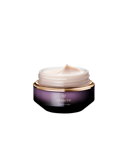 Photo of an open jar of SYNACTIF body cream, revealing the smooth, pale pink cream inside. The jar features a deep violet gradient with gold accents against a dark background.