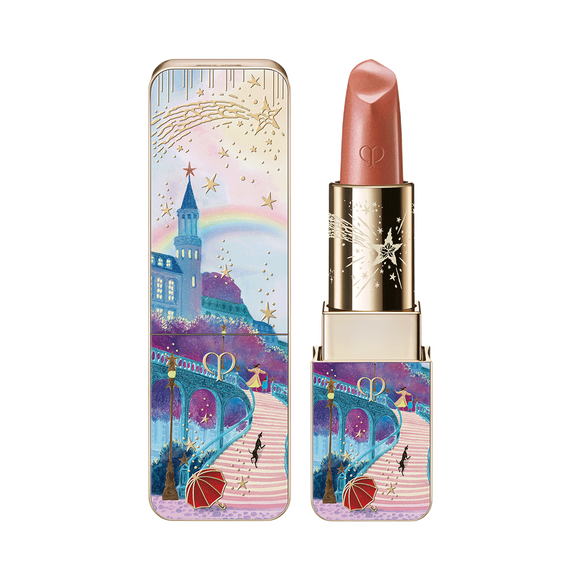 Photo of the 26 AW Holiday Collection limited-edition LIPSTICK. A highly detailed scenic illustration of a path toward a castle with a rainbow and two figures is depicted on the square-tubed gold bullet. The lipstick is shown open beside its matching outer case and a texture swatch.